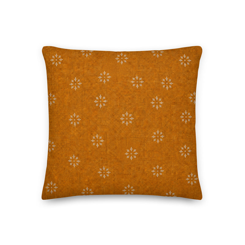 Orange pillow with white floral pattern on a white background