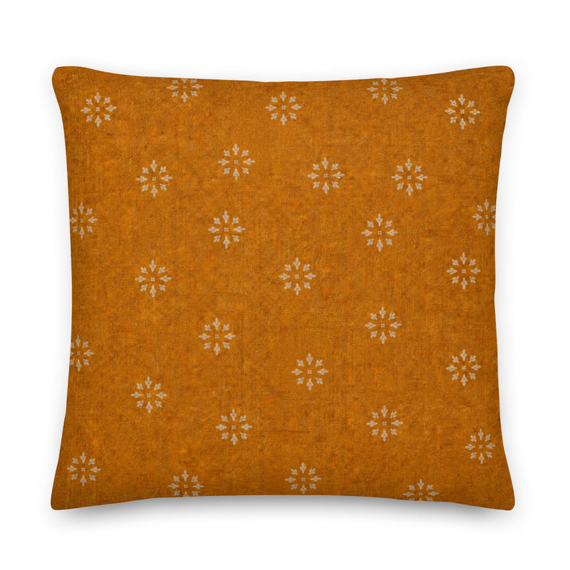 Orange pillow with white floral patterns on a white background