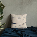 Floral patterned pillow on a textured wall with a plant and dark fabric.