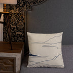 Decorative pillow with mountain design on a gray sofa next to a wooden side table and lamp.