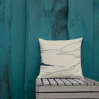 Decorative pillow with abstract design on a wooden bench against a teal wall