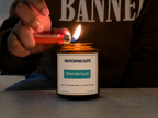 Moodscape Wanderlust candle in a amber jar lit by the owner wearing BANNED hoodie