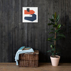 Abstract art piece on a dark wooden wall with a woven basket and plant below.