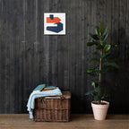 Wicker basket with towels and books next to a potted plant against a dark wooden wall with abstract art.