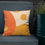 Decorative pillow with orange and yellow design on a blue chair next to a potted plant.