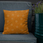 Orange patterned pillow on a gray couch with a plant in the background