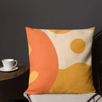 Decorative pillow with orange and yellow abstract design on a chair against a dark wall.