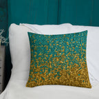 Decorative pillow with gold and teal pattern on a white couch against a teal wall.