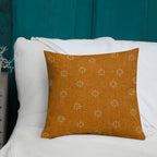 Orange pillow with floral pattern on a white surface against a teal wall