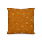 Orange pillow with white floral pattern on a white background