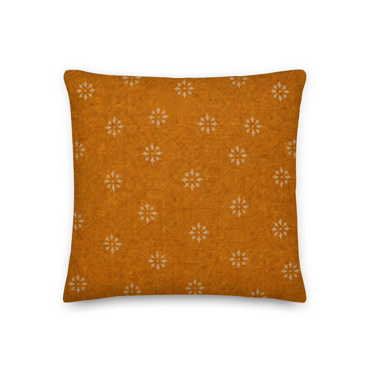 Orange pillow with white floral pattern on a white background