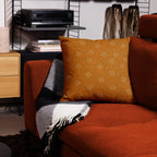 Orange pillow with a pattern on a red couch in a living room setting.
