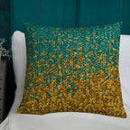Decorative pillow with gold and teal pattern on a white surface against a teal background