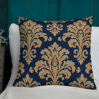 Decorative pillow with gold damask pattern on a blue background, placed on a white chair against a teal wall.
