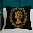 Decorative pillow with a gold portrait design on a black background, placed on a white surface.