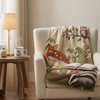 Baby blanket with cottage core vibe in woodland setting including baby fox, owl, mushrooms and trees. Placed over an armchair in a cozy sunlit corner.